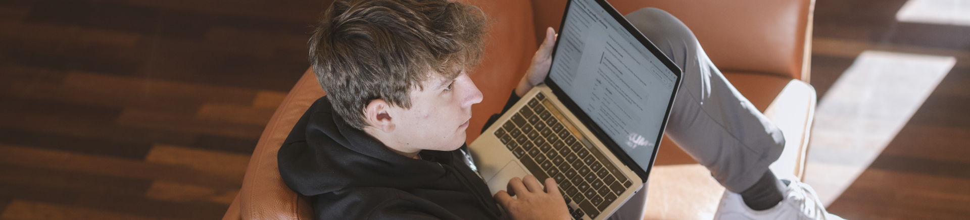 Studerende sidder i lænestol og bruger bærbar computer i indendørs miljø